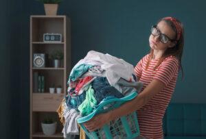  frustrierte Frau, die einen Wäschekorb voller schmutziger Wäsche hält