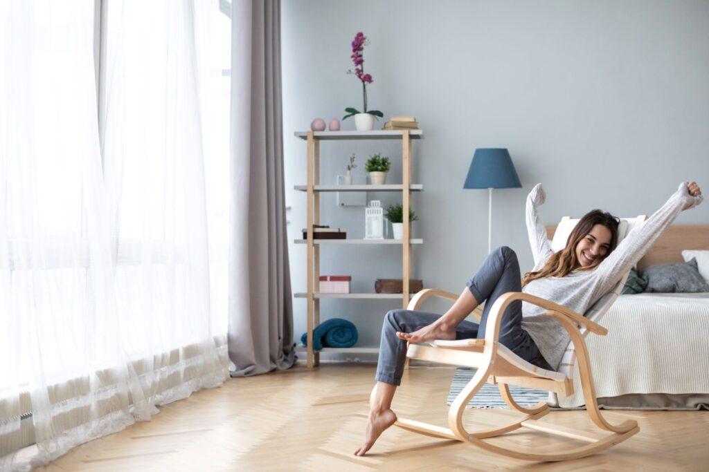 Glückliche Frau ruht bequem sitzen auf modernen Stuhl im Wohnzimmer zu Hause.