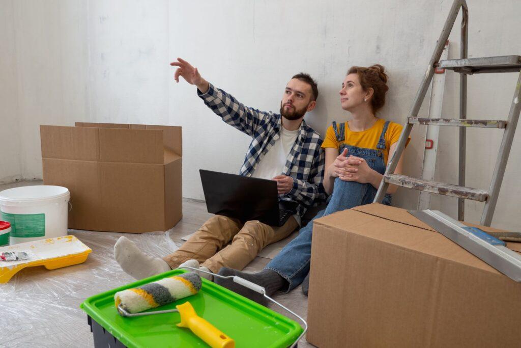 Paar plant Renovierung mit Laptop in leerer Wohnung.