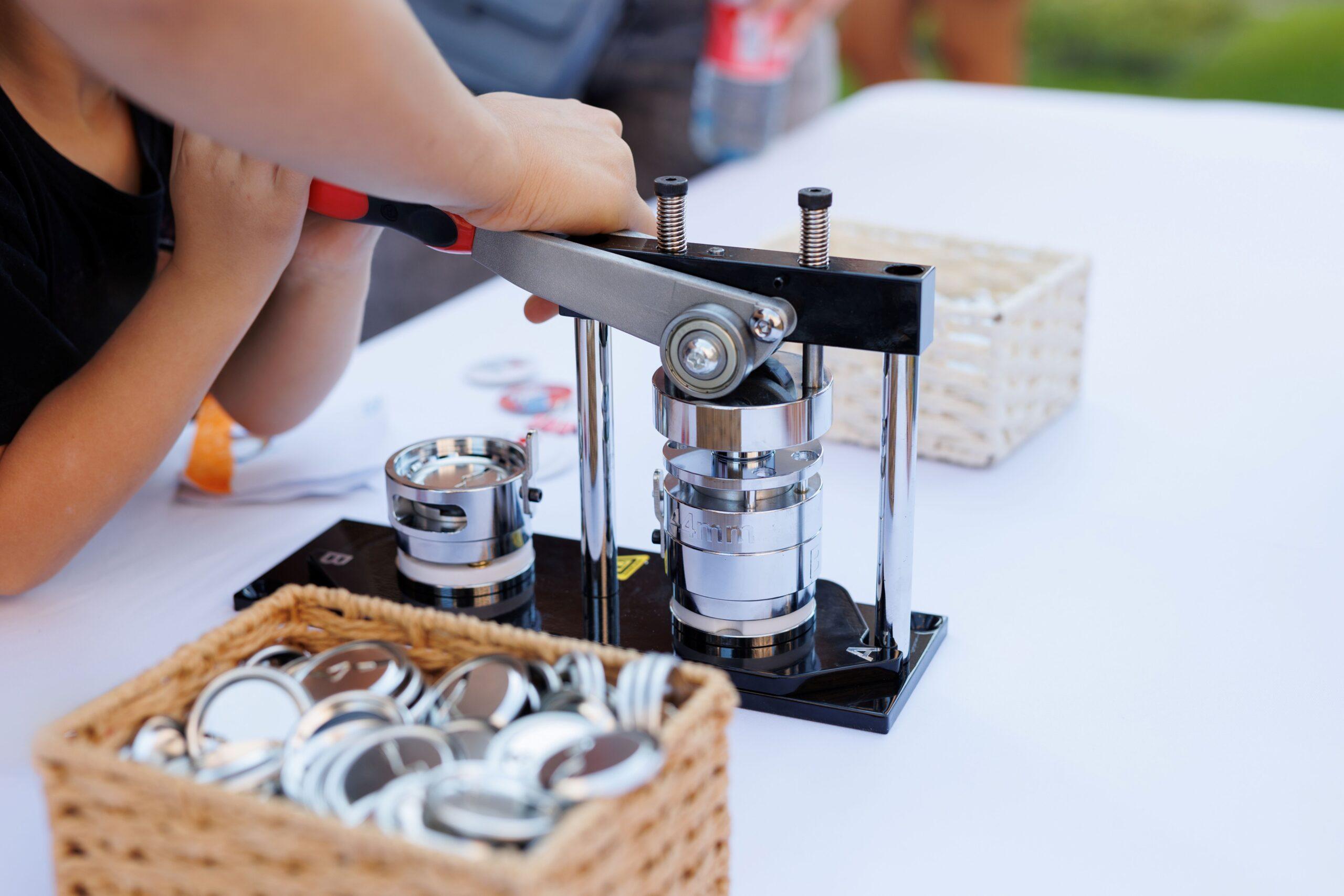 Kind benutzt Buttonmaschine am Basteltisch