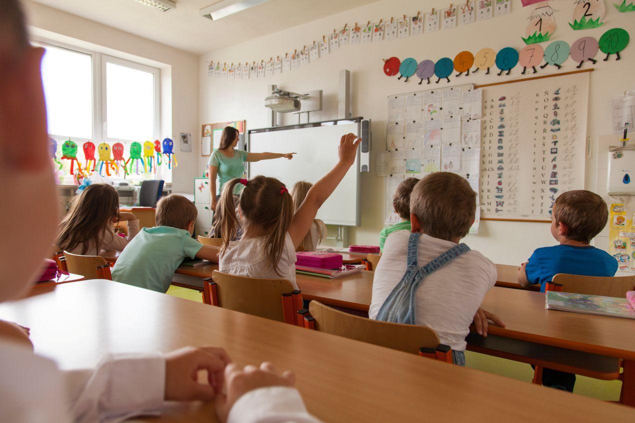 Kinder im Unterricht einer bilingualen grundschule berlin, Lehrerin erklärt Inhalte am Whiteboard
