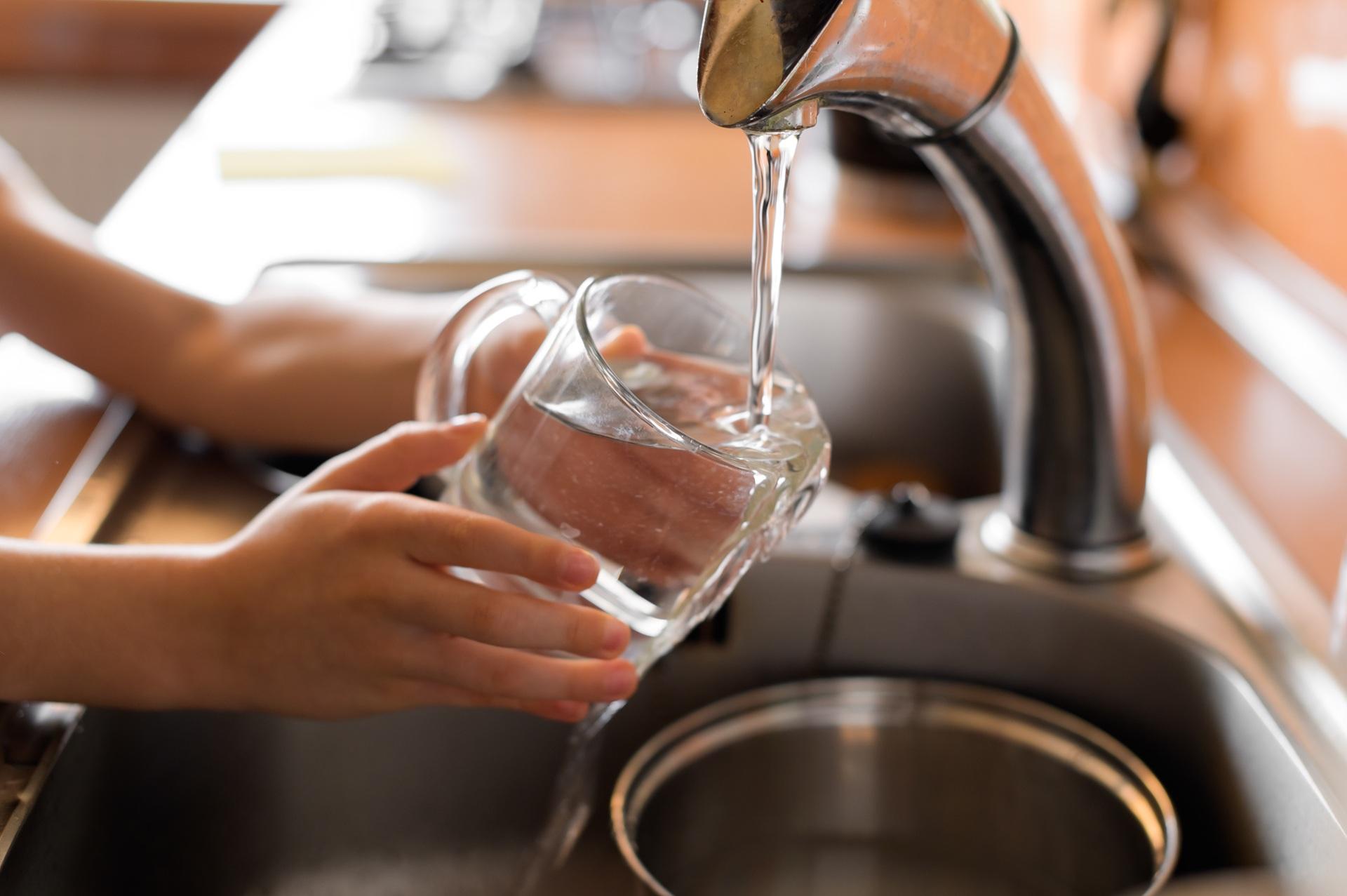 Hände füllen Glas mit Leitungswasser | Wasserfilteranlage
