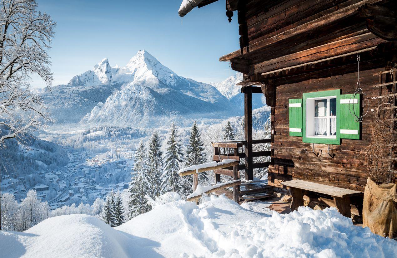 Rustikale Skihuette Oesterreich mit gruener Fensterlaeden und Aussicht auf Alpenlandschaft im Winter