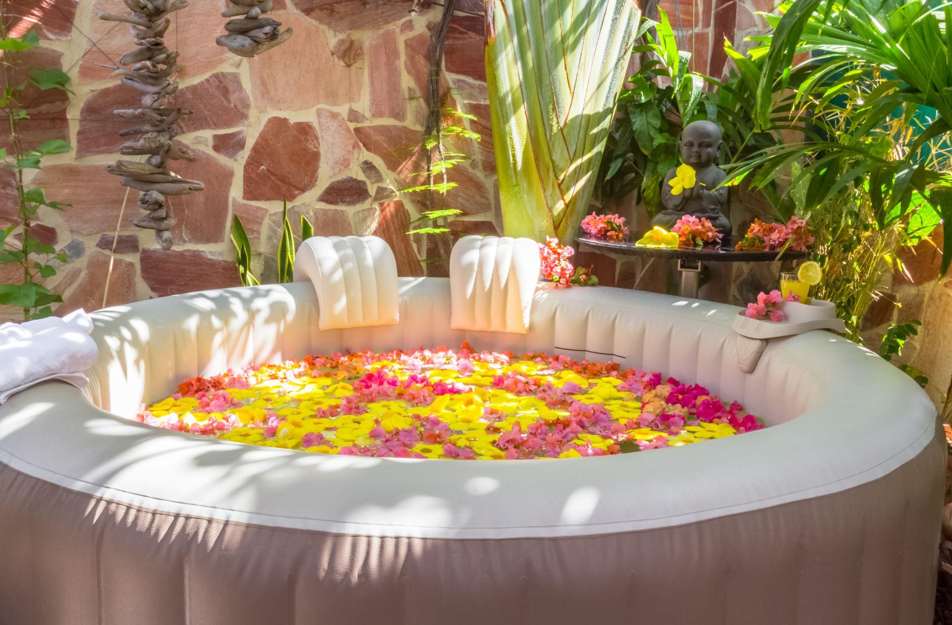 Aufblasbarer Whirlpool mit Blüten im tropischen Garten, symbolisiert Wellness und stilvolles Whirlpool-Zubehoer fuer zuhause